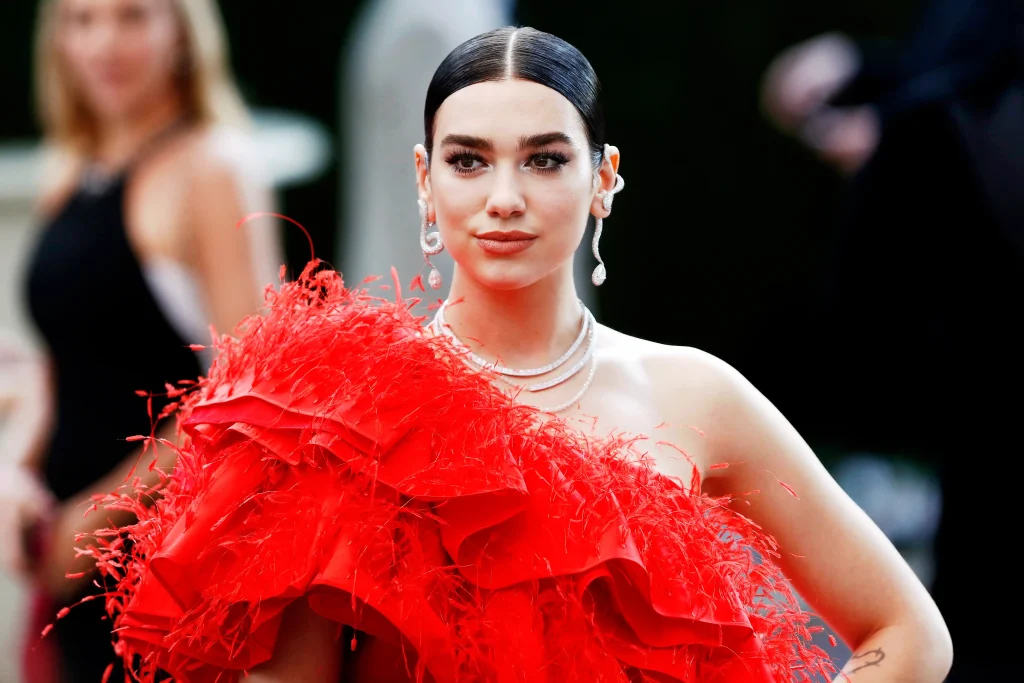 Sleek hair, pearl necklace, red feathers.